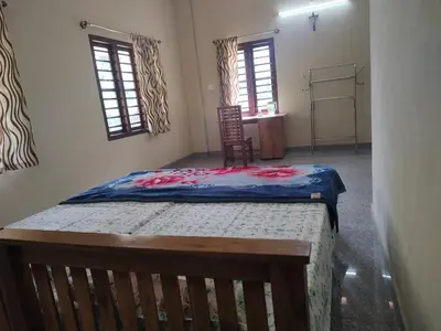 a bedroom with a bed in a room with two windows at Bridgettine Paradise in Sultan Bathery