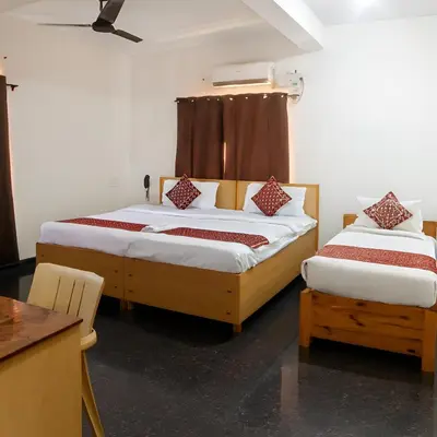 a bedroom with two beds and a desk and a table at Stayz Royale - Mysuru near Mysuru Palace in Mysore