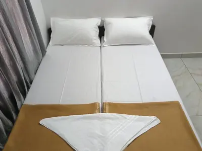 two beds with white sheets and pillows in a room at GG Residency INN in Palakkad