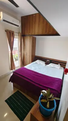 a bedroom with a bed and a potted plant on a table at Steeva service apartment in Mysore