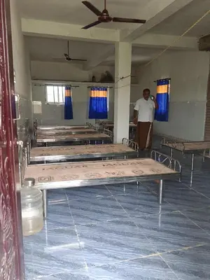 a man standing in a room with rows of beds at Sona rooms in Coimbatore