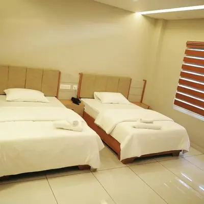a bedroom with two beds with white sheets and a window at Neom Inn in Wayanad