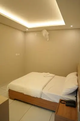 a bedroom with a bed with a fan on the wall at Neom Inn in Wayanad