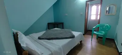 a blue bedroom with a bed and a chair at Jay bahadur Cottages and home stay in Ooty