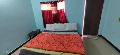 a small bedroom with a bed with a red comforter at Jay bahadur Cottages and home stay in Ooty