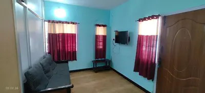 a living room with red curtains and a tv at Jay bahadur Cottages and home stay in Ooty