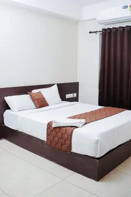 two beds in a hotel room with white and brown at Gokulam suits guruvayur in Guruvāyūr
