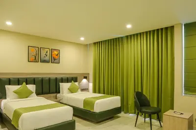 two beds in a hotel room with green curtains at Chaliyar Resorts