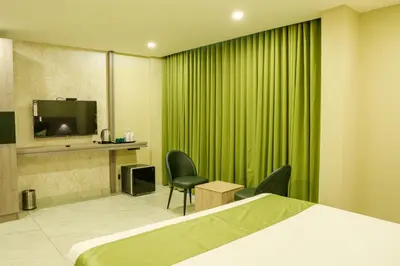 a hotel room with a bed and a tv and green curtains at Chaliyar Resorts