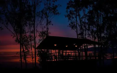 a gazebo with a sunset in the background at ivaana resorts mysore in Mysore