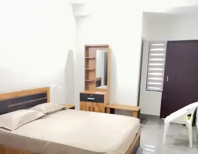 a bedroom with a bed and a desk and a chair at Hotel Alka Inn Residency Wayanad in Sultan Bathery