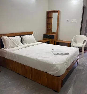 a bedroom with a large bed and a chair at Hotel Alka Inn Residency Wayanad in Sultan Bathery