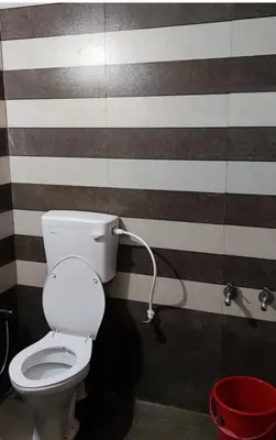 a bathroom with a toilet with stripes on the wall at hilldown cottage in Ooty