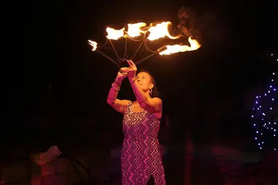 a woman holding up a string with fire at Spirit of the Wild Mountain Retreat in Palakkad