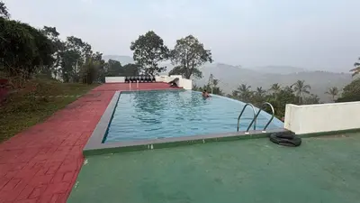 a large swimming pool with a person in the water at Metta Heaven Farm Resort in Kodenchery