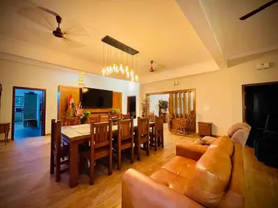 a living room with a table and a dining room at Lush Orchard in Kizhake Chālakudi