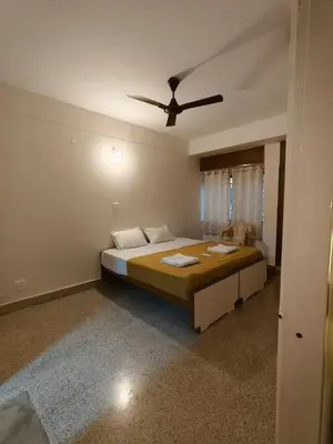 a bedroom with a large bed with a ceiling fan at Raviudaya-2bhk in Mysore