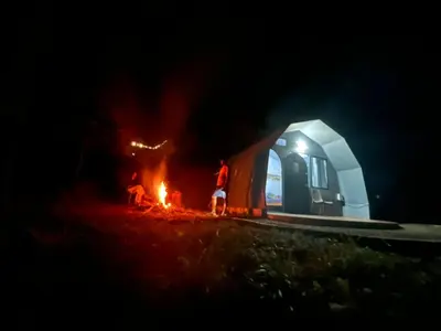two people standing around a fire in front of a tent at Spirit of the Wild Mountain Retreat Attapadi in Attappādi
