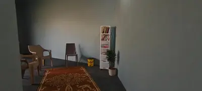 a living room with chairs and a book shelf at Spirit of the Wild Mountain Retreat Attapadi in Attappādi