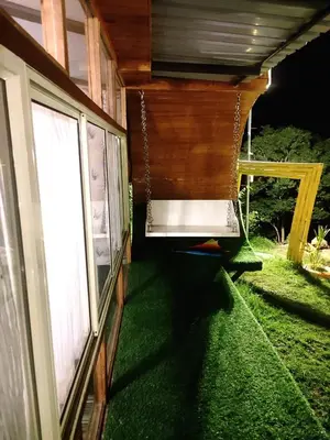 a porch of a house with green grass next to a window at The Farmville kodaikanal in Kodaikānāl