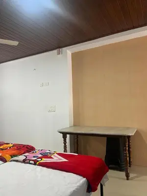 a room with a bed with a table next to it at Pookode Service Villa in Vythiri