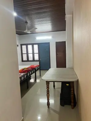 a room with two beds and a table in it at Pookode Service Villa in Vythiri