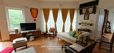 a living room with a couch and a tv at Sunflower Villa Cottage Coonoor in Coonoor