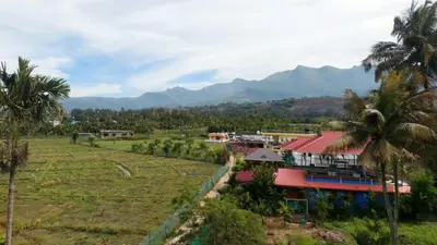 a resort with palm trees and mountains in the background at Caramel stay in Marayoor