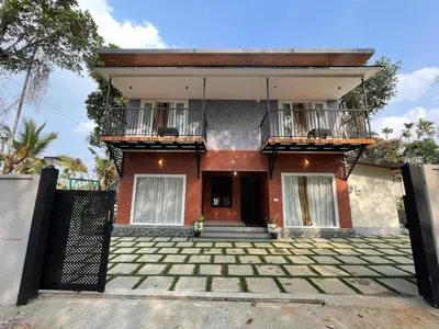 a house with a balcony and a driveway at Nellarachal Homestay in Ambalavayal