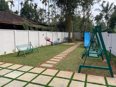 a playground with benches and a swing set at Nellarachal Homestay in Ambalavayal