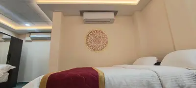 a bedroom with two beds and a air conditioner on the wall at Shri Bhagawathi Residency in Palani