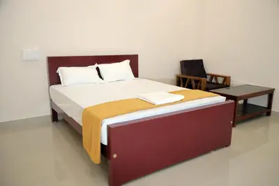 a bedroom with a large bed and a table at Amritha Lodge in Kollengode