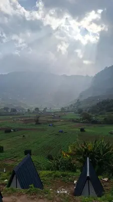 two tents in a field with mountains in the background at Secret valley vattavada in Vattavada