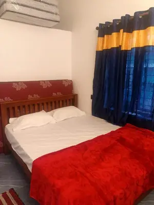 a bedroom with a bed with a red blanket at Sandal Homestay in Marayoor