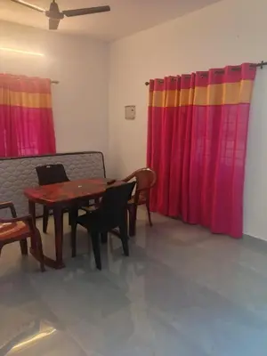 a dining room with a table and chairs and colorful curtains at Sandal Homestay in Marayoor