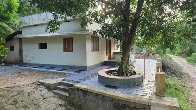 a house with a tree in front of it at Happy Home Stay in Palakkad