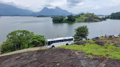 a bus parked on a hill next to a body of water at Happy Home Stay in Palakkad