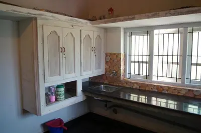 a kitchen with white cabinets and a sink and two windows at The Marayoor in Marayoor