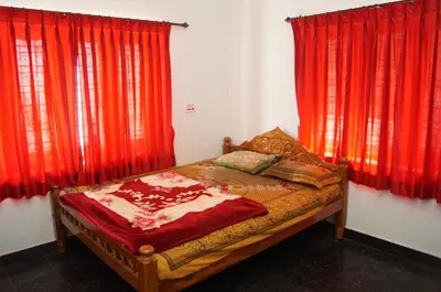 a bed in a room with red curtains at The Marayoor in Marayoor