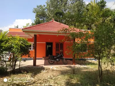 a motorcycle parked in front of a red house at The Marayoor in Marayoor