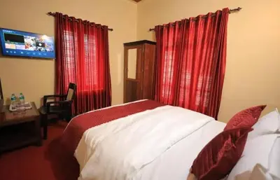 a bedroom with a bed with red curtains and a television at Hamai town villa in Ambalavayal