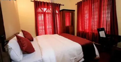 a bedroom with red curtains and a white bed with pillows at Hamai town villa in Ambalavayal
