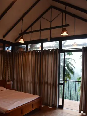 a bedroom with a bed and a large window at Waterfall View Stay Chappanthotam Kozhikode in Kuttyādi