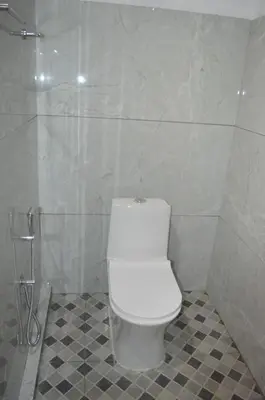 a bathroom with a white toilet in a shower at Waterfall View Stay Chappanthotam Kozhikode in Kuttyādi