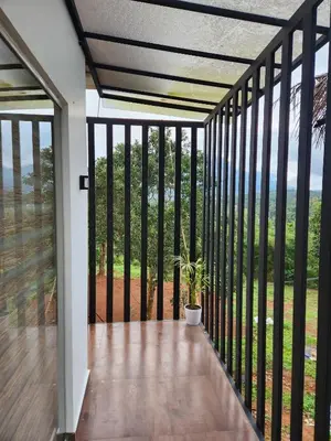 a screened porch with a potted plant on it at Shade trees in Padinjarathara