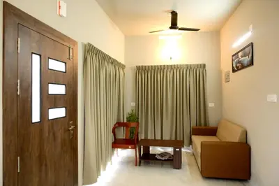 a living room with a couch and a chair and a door at Shade trees in Padinjarathara