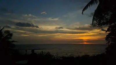 a person watching the sunset on the beach at Razena Beach in Green Island