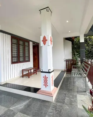 a porch of a house with a pillar and a bench at Edakkal Pool Villa in Ambalavayal
