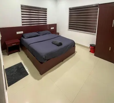 a bedroom with a bed with a blue comforter at Edakkal Pool Villa in Ambalavayal