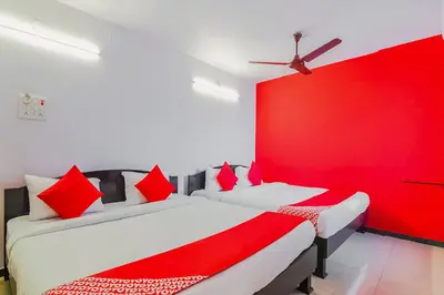 two beds in a room with red and white at Super Hotel O By OYO Maruthi Gandhi Park in Coimbatore